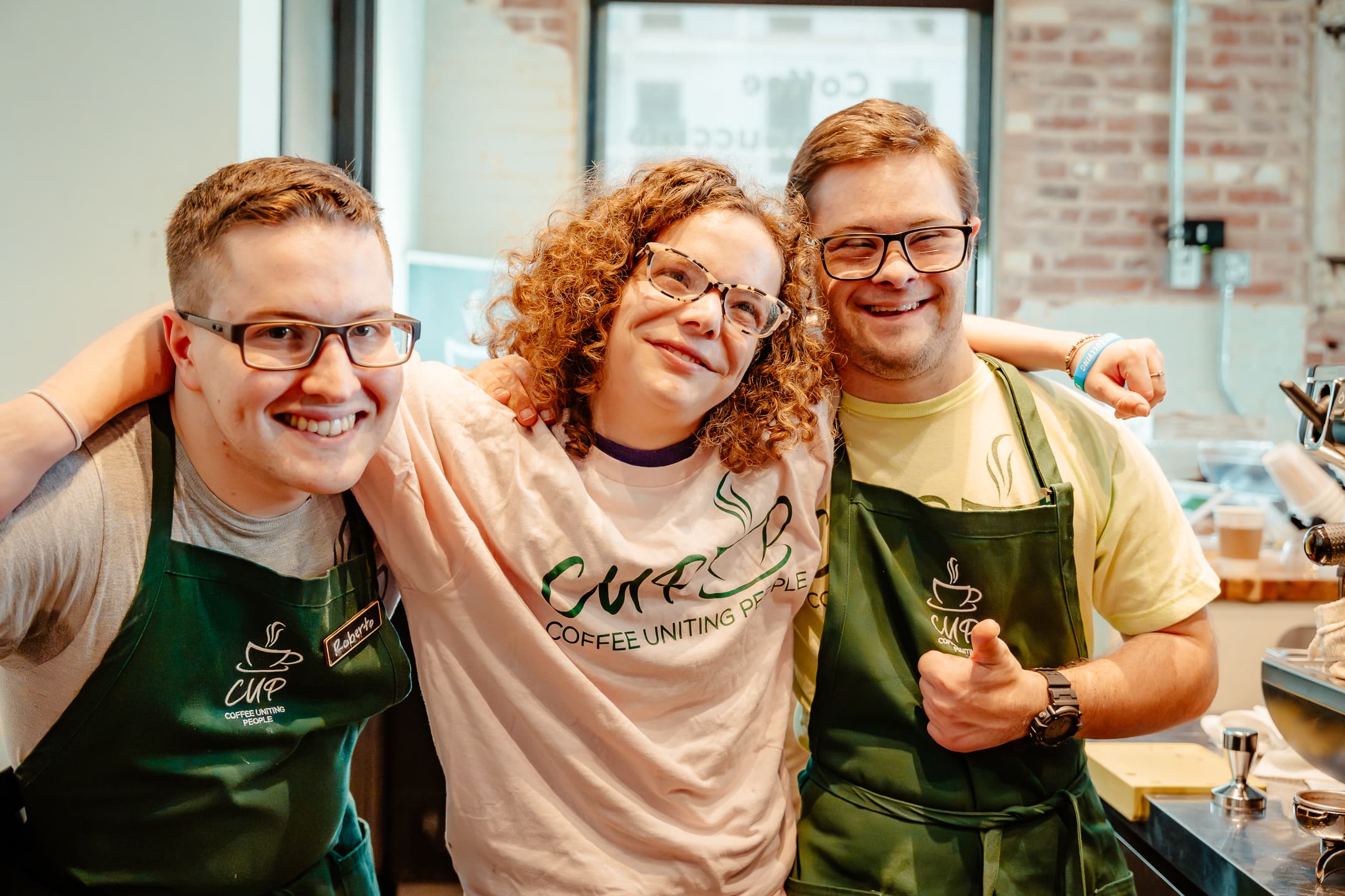 Three CUP team members laughing together against a brick wall